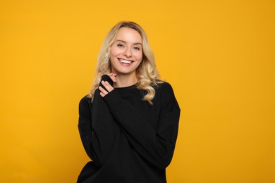 Photo of Happy woman in stylish warm sweater on orange background