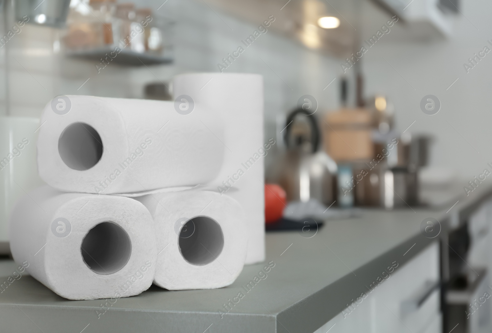 Photo of Rolls of paper towels on table in kitchen, space for text