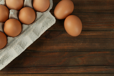 Photo of Raw chicken eggs on wooden table, flat lay. Space for text