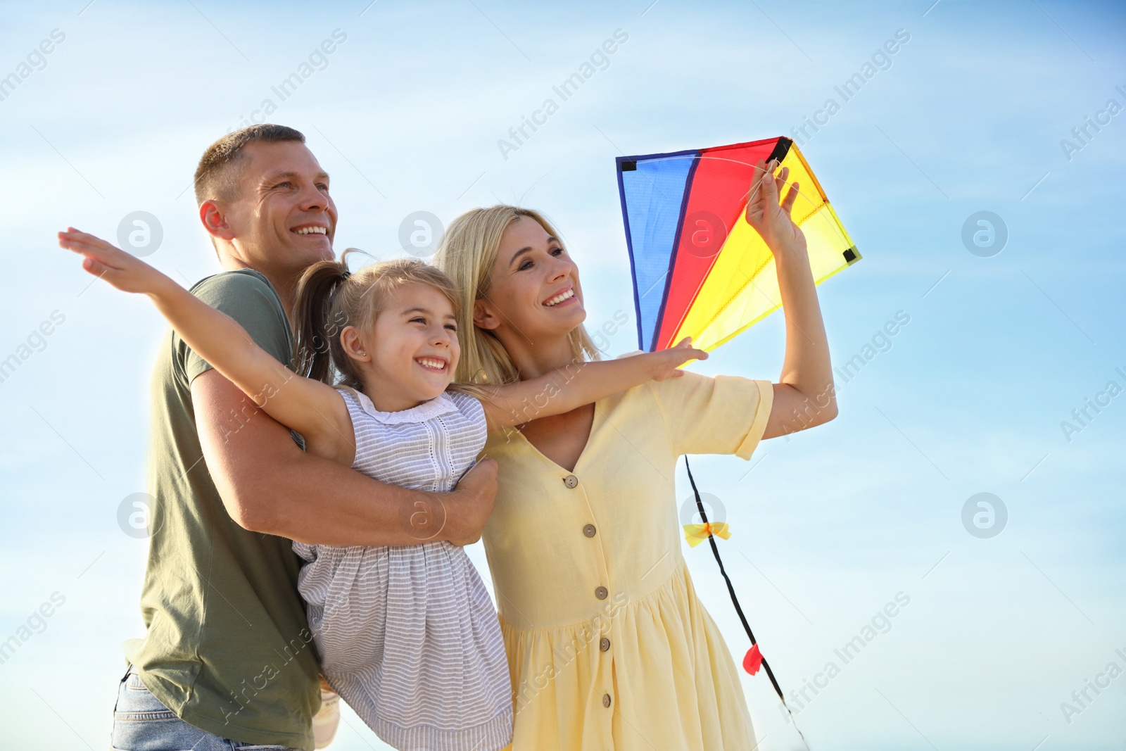 Photo of Happy parents with their child playing with kite on beach. Spending time in nature