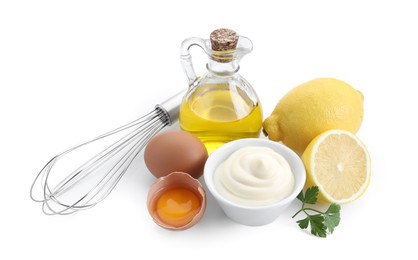 Photo of Tasty mayonnaise sauce in bowl, whisk and ingredients isolated on white
