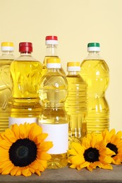 Photo of Bottles of cooking oil and sunflowers on wooden table