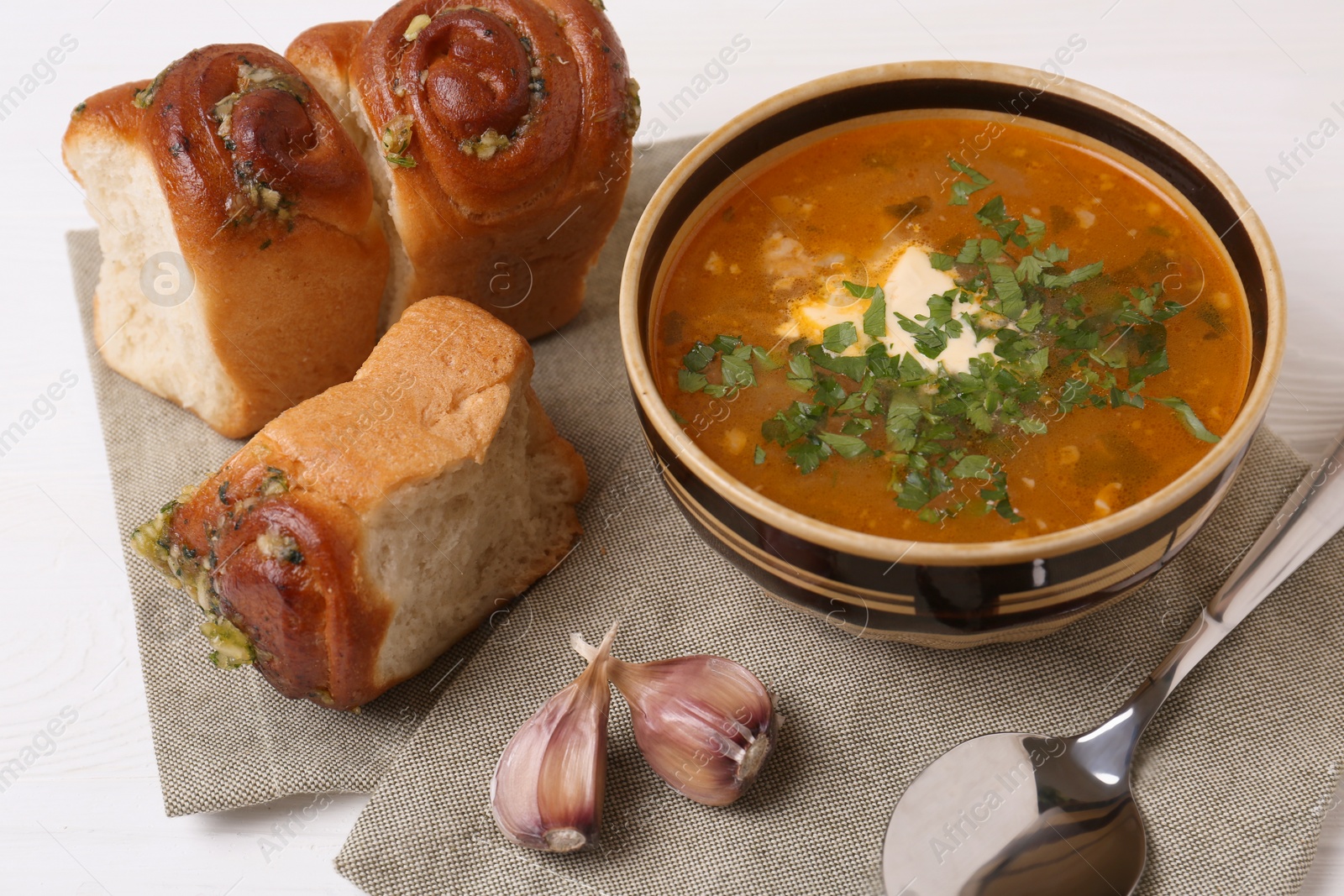 Photo of Delicious borsch served with pampushky on white wooden table. Traditional Ukrainian cuisine