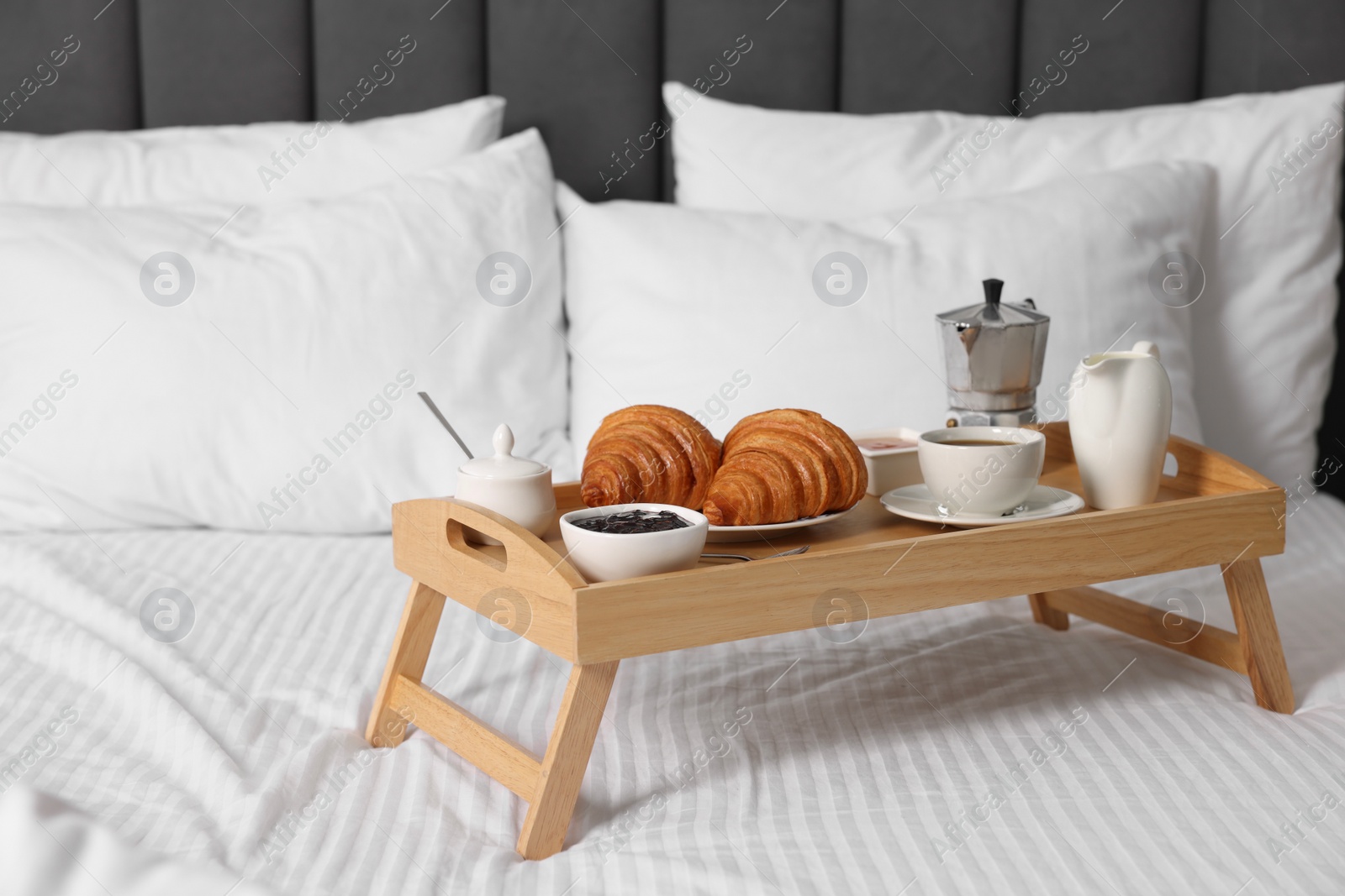 Wooden tray with tasty breakfast on bed at home Photo of Wooden tray with tasty breakfast on bed at home