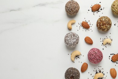 Delicious vegan candy balls and nuts on white table, flat lay. Space for text