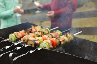 Photo of Couple having barbecue party outdoors, focus on brazier with meat and vegetables