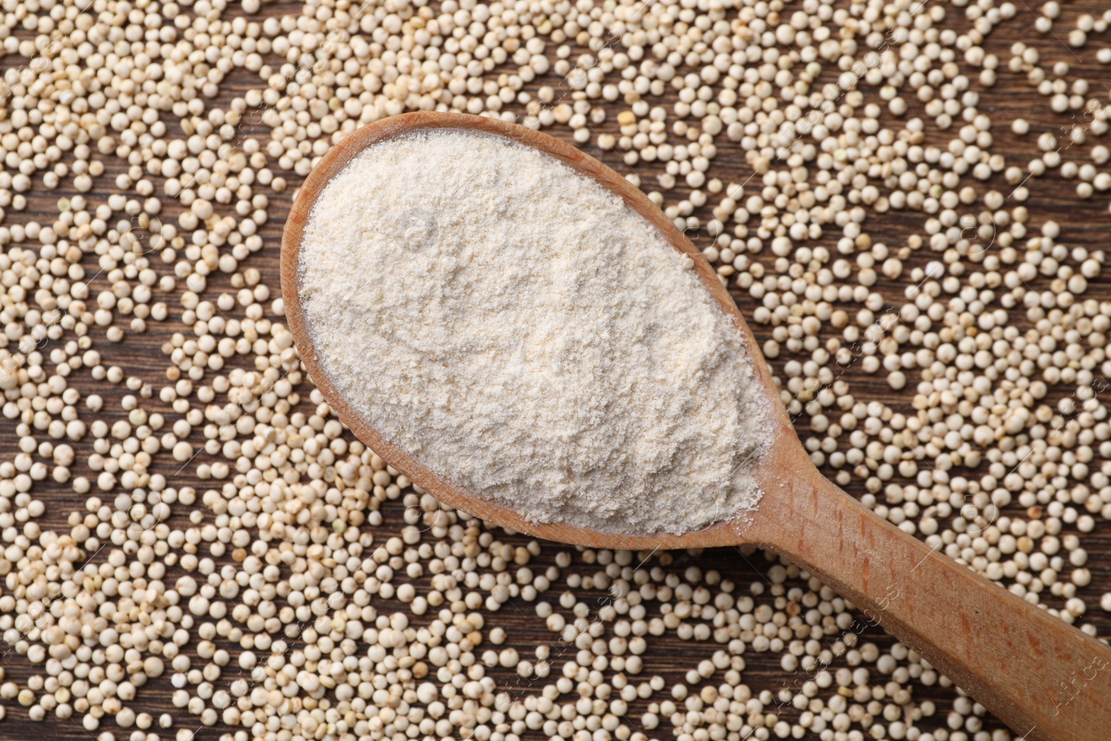 Photo of Spoon with quinoa flour and seeds on wooden table, top view