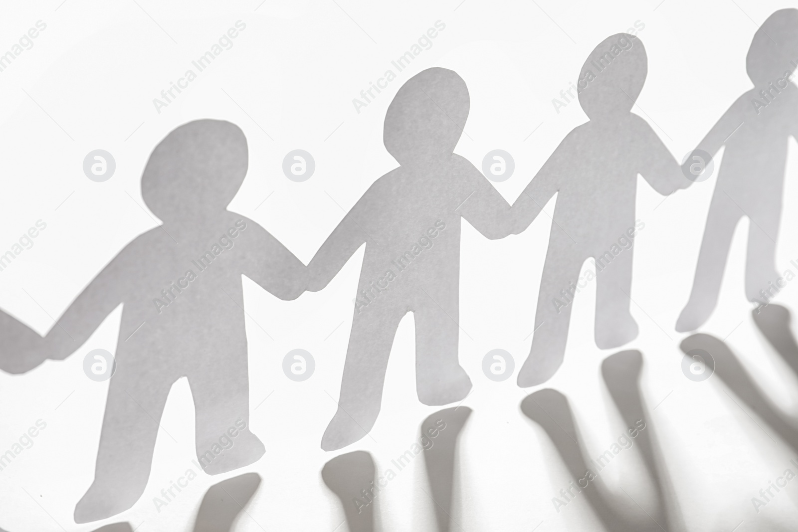 Photo of Paper people holding hands on light background. Unity concept