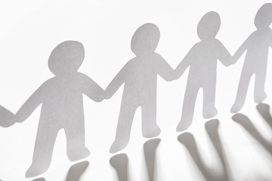 Photo of Paper people holding hands on light background. Unity concept