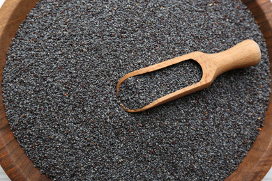 Photo of Poppy seeds and wooden scoop in bowl, closeup