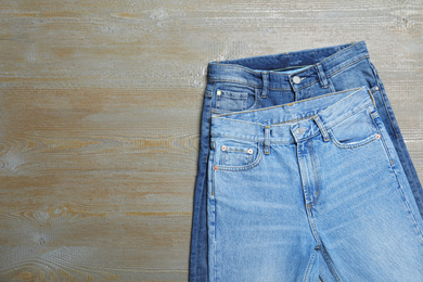 Photo of New stylish jeans on wooden background, flat lay. Space for text