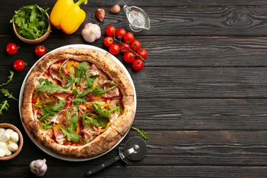 Photo of Tasty pizza with meat and arugula on black wooden table, flat lay. Space for text