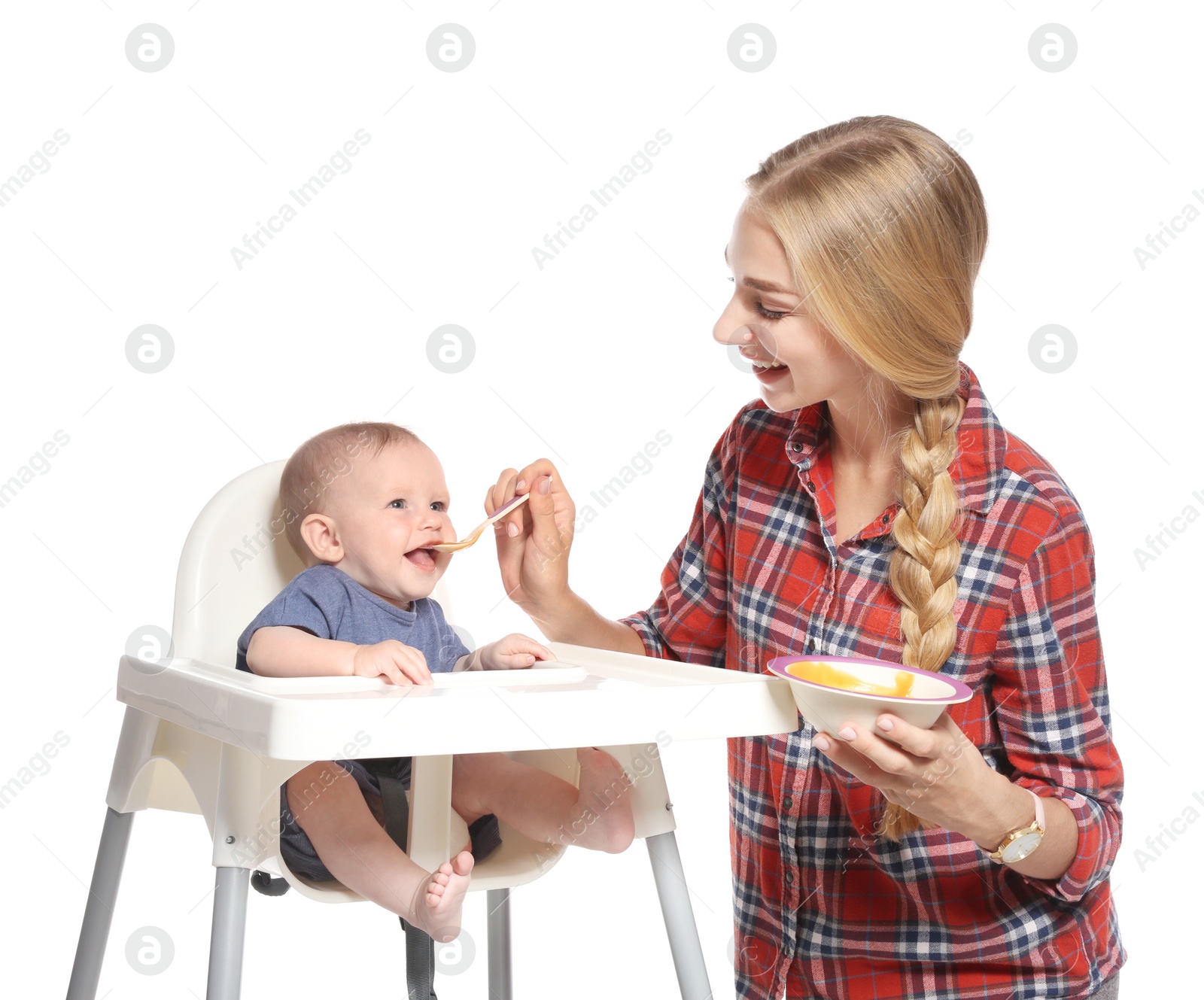 Photo of Woman feeding her child in highchair against white background. Healthy baby food