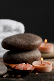 Beautiful composition with spa stones and burning candles on wooden table, closeup