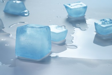 Photo of Crystal clear ice cubes on light blue background