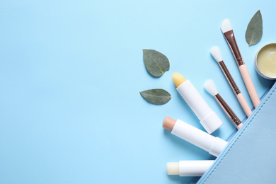 Flat lay composition with hygienic lipsticks on light blue background, space for text