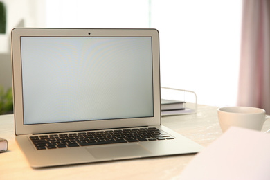 Modern laptop and cup of coffee on white table indoors. Space for design