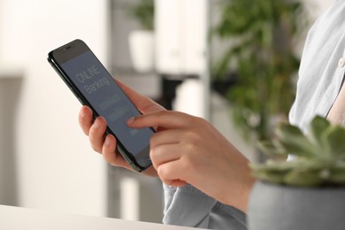 Photo of Woman using online banking app on smartphone indoors, closeup