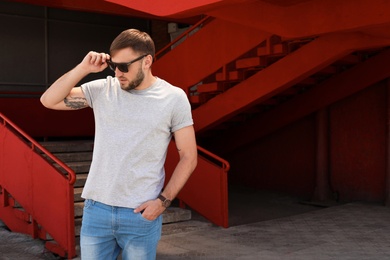 Photo of Young man wearing gray t-shirt on street. Urban style