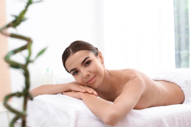 Photo of Beautiful young woman lying on massage table in spa salon