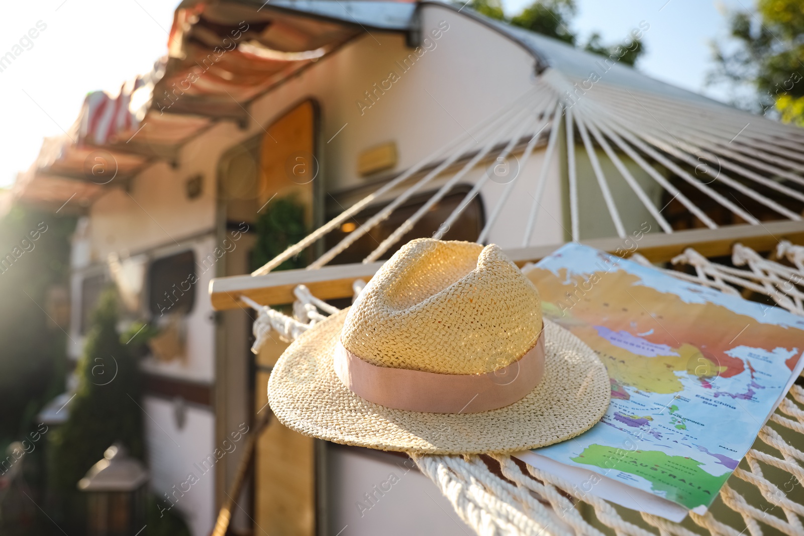 Photo of Comfortable hammock with hat and world map near motorhome outdoors on sunny day