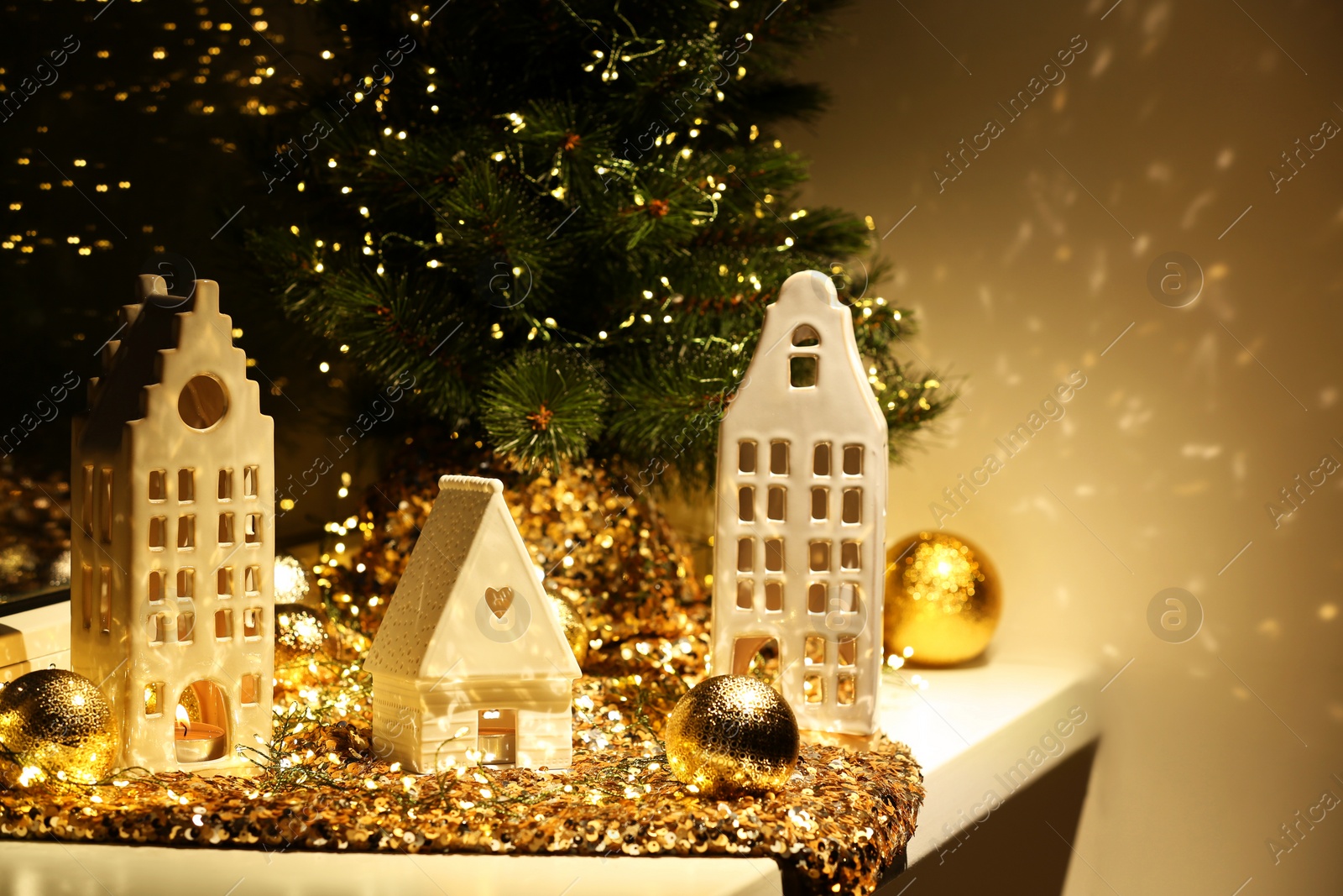 Photo of Beautiful decorative houses, baubles and small Christmas tree on window sill indoors