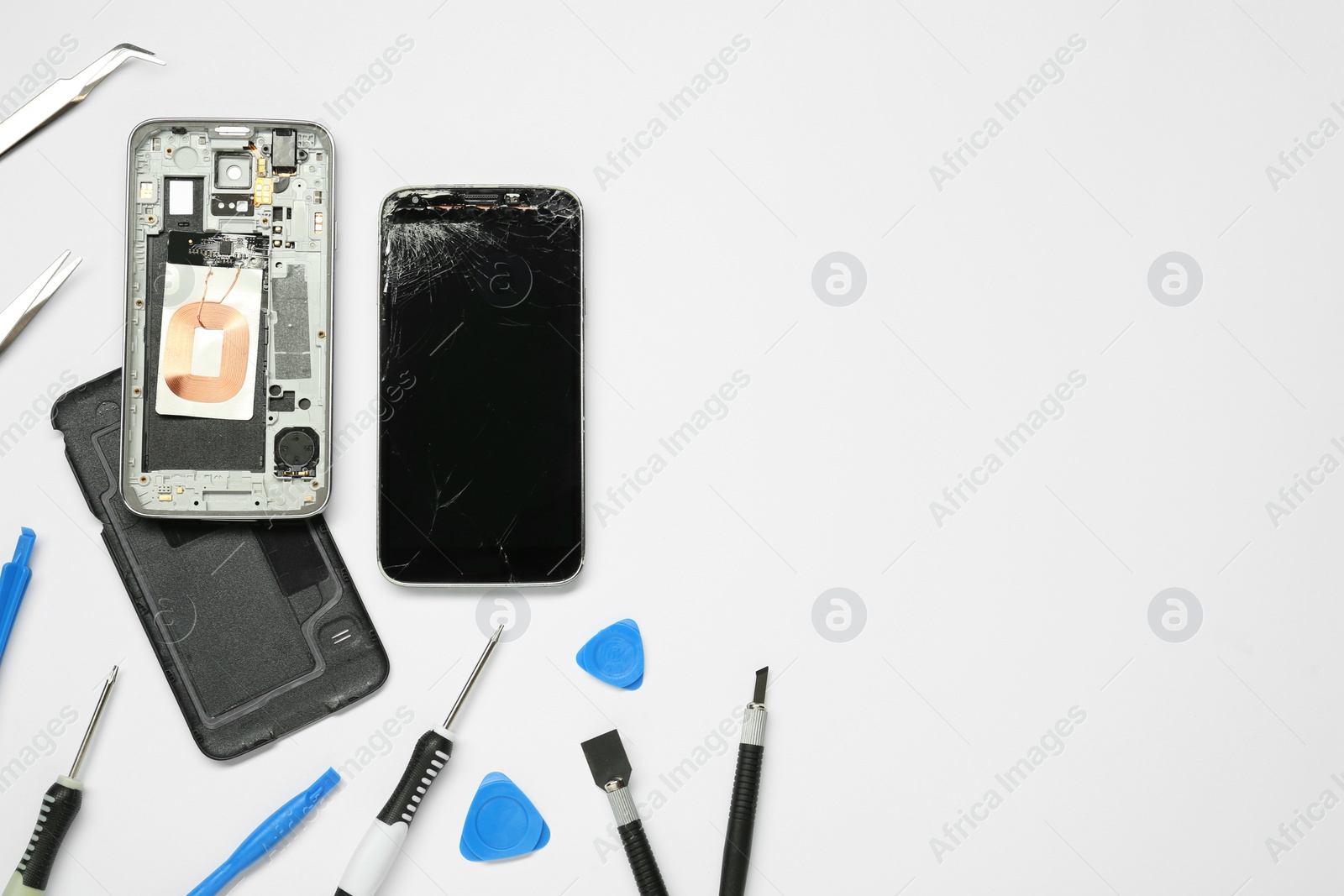 Photo of Damaged smartphone and repair tool set on white background, flat lay. Space for text