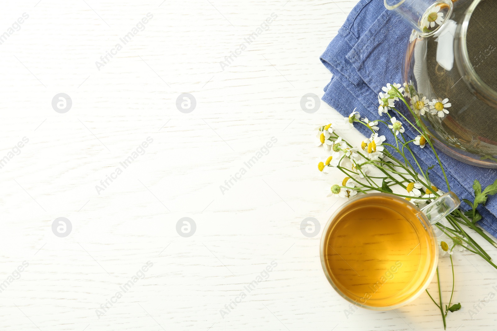 Photo of Flat lay composition with tea and chamomile flowers on white wooden table. Space for text