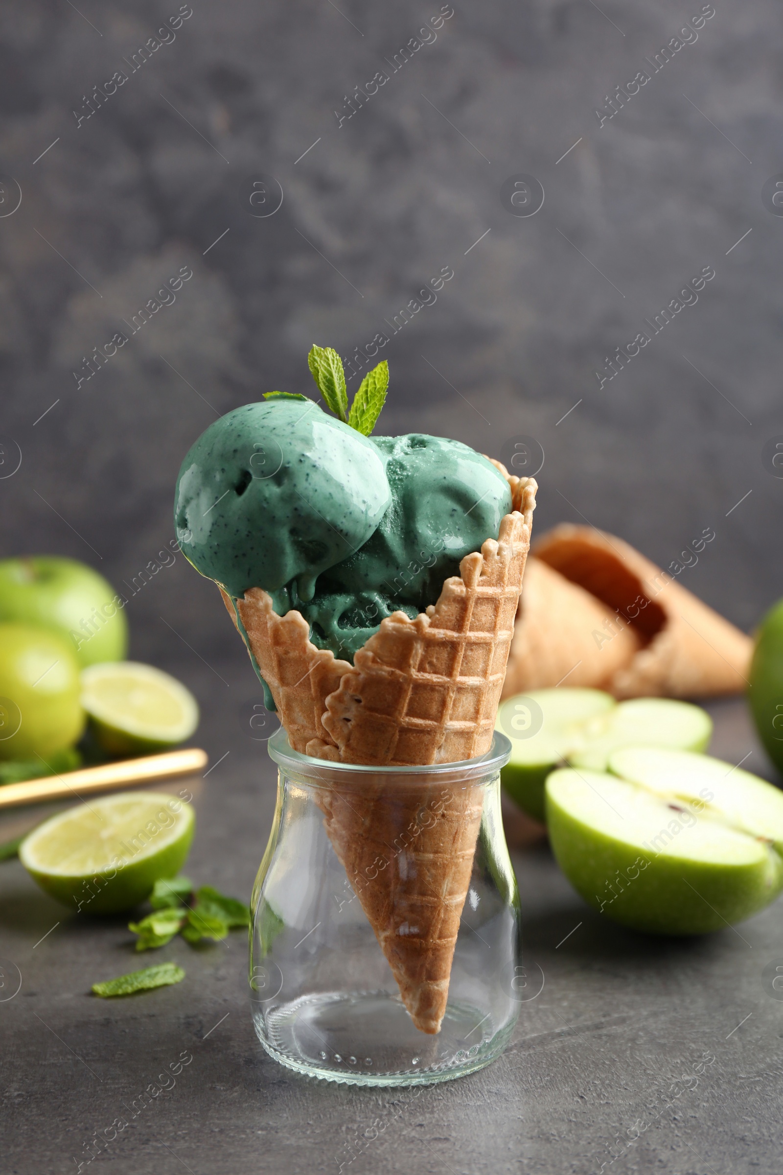 Photo of Composition with delicious spirulina ice cream cone on table against grey background