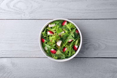 Delicious salad with radish, lettuce and arugula on light gray wooden table, top view