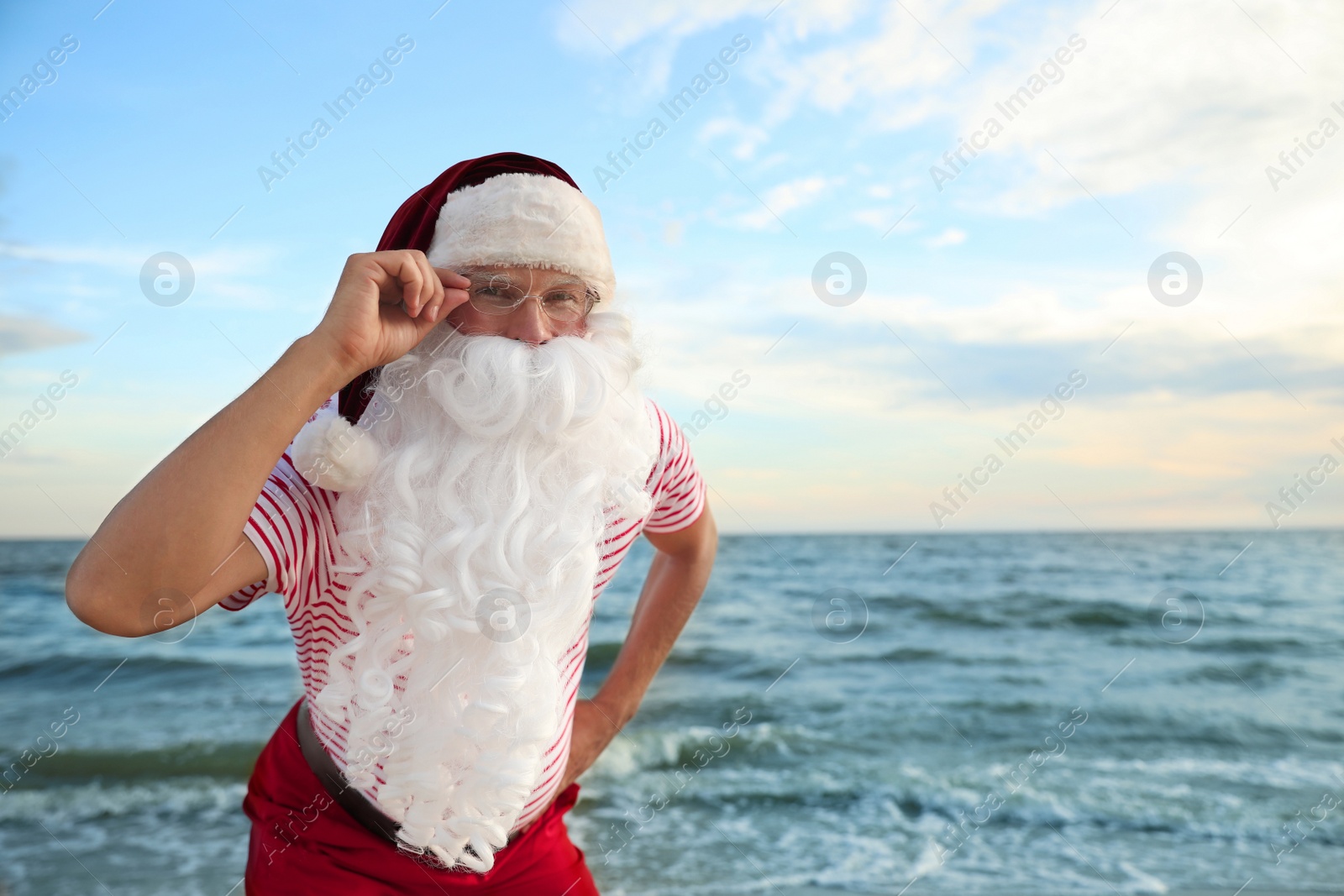 Photo of Santa Claus on beach, space for text. Christmas vacation