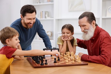 Family playing chess together at table in room