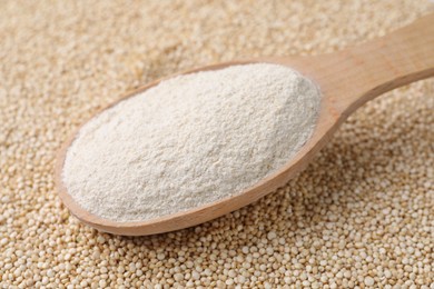 Photo of Wooden spoon with quinoa flour on seeds, closeup