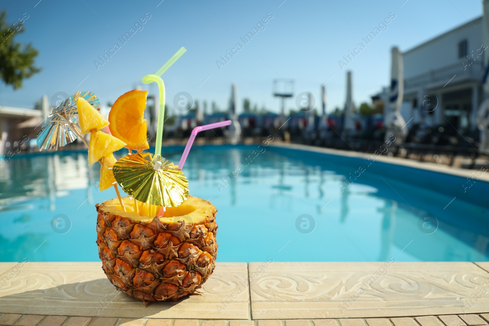 Photo of Tasty tropical cocktail on edge of swimming pool. Party drink