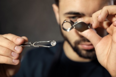 Male jeweler evaluating precious gemstone in workshop, closeup