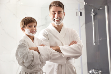 Photo of Dad and son with shaving foam on faces in bathroom