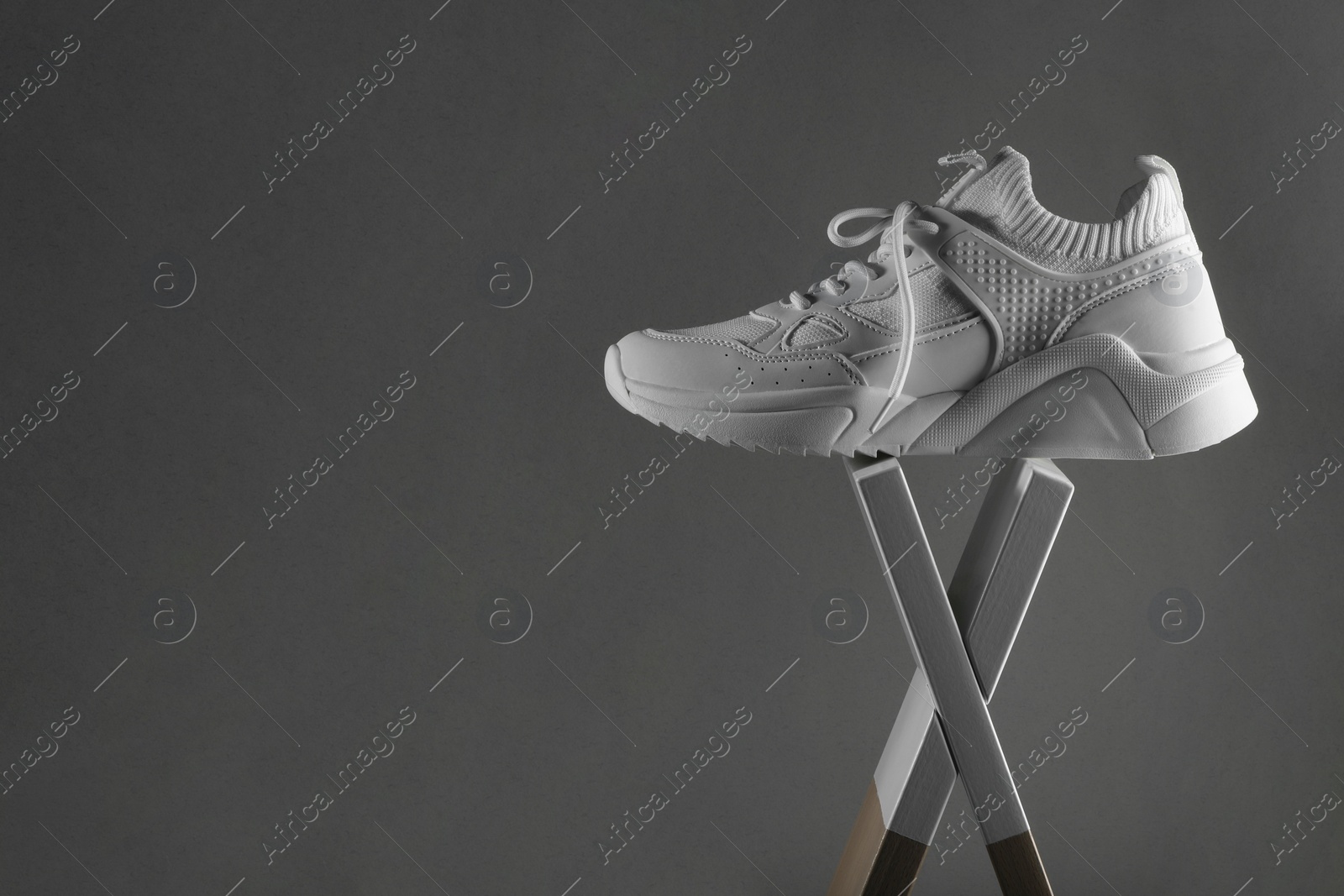 Photo of One stylish white sneaker on grey background, space for text