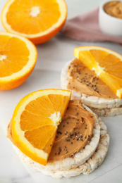 Photo of Puffed rice cakes with peanut butter and orange on white table