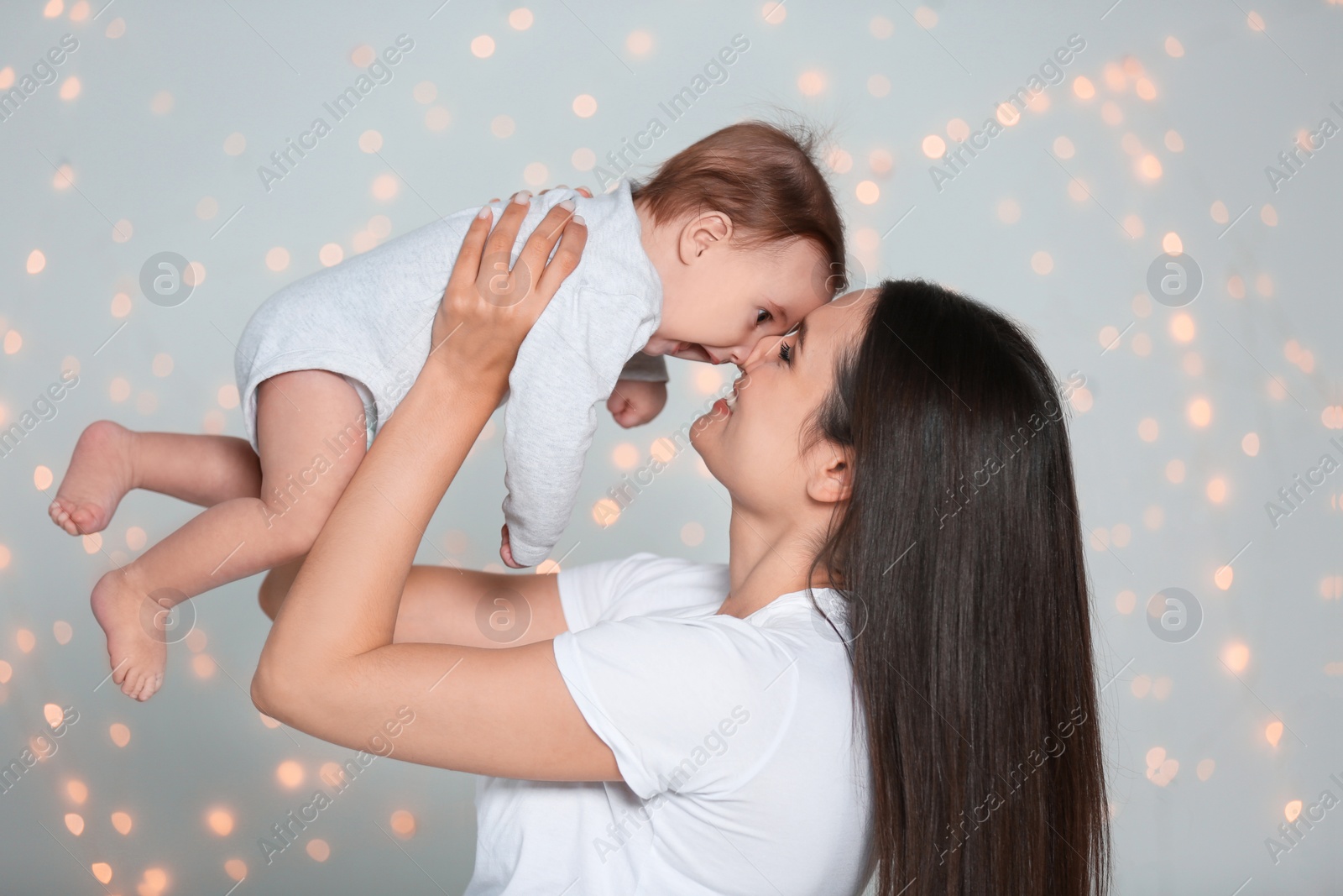 Photo of Young mother with her cute little baby against defocused lights