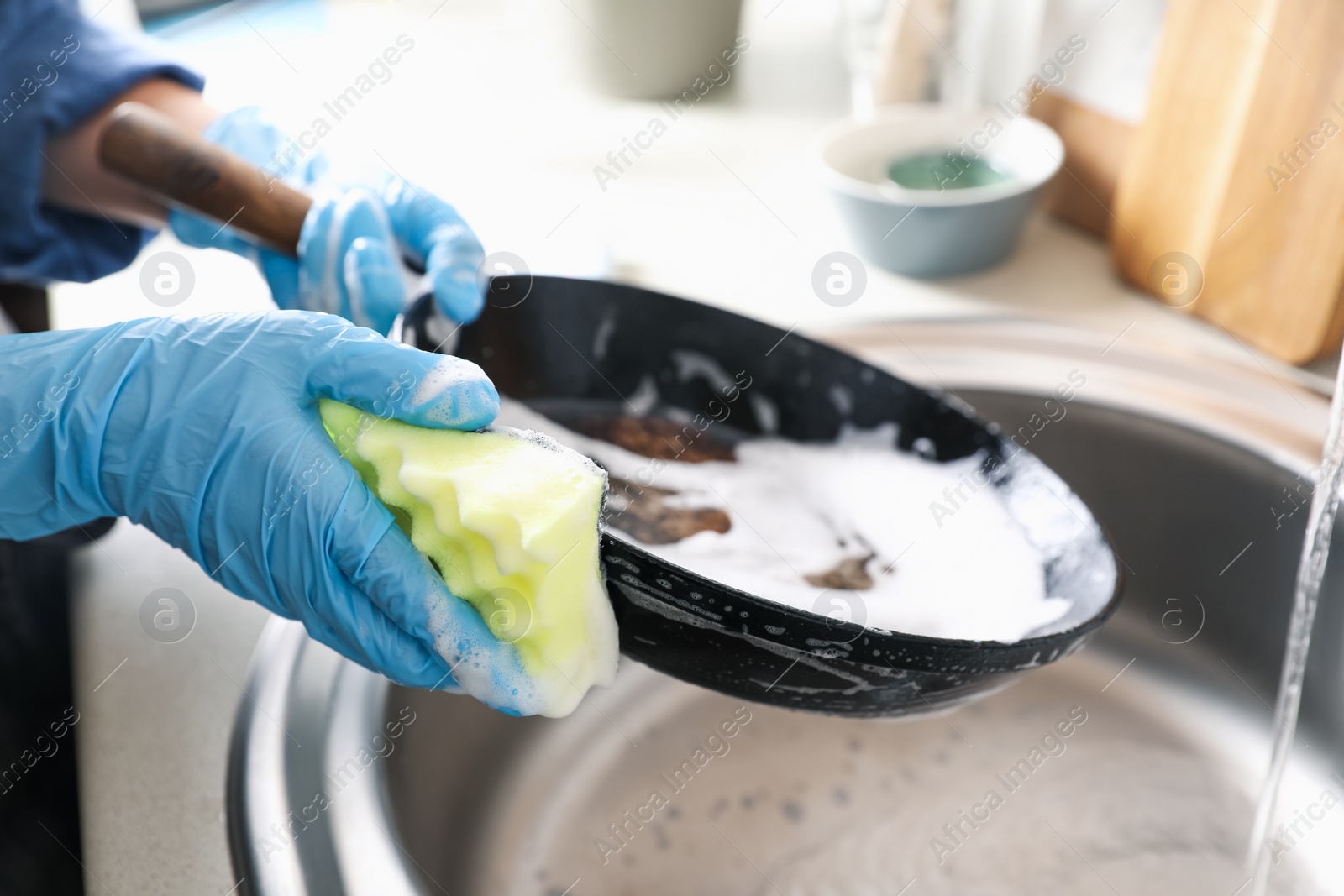 Photo of Woman washing dirty frying pan in sink indoors, closeup