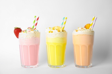 Photo of Glasses of tasty milk shakes on white background