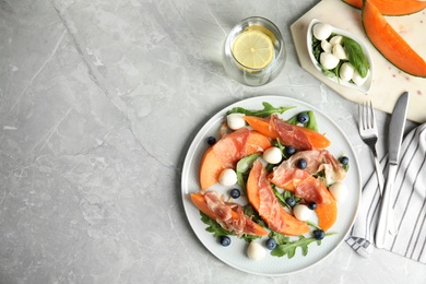 Photo of Flat lay composition of fresh melon with prosciutto on light grey marble table. Space for text