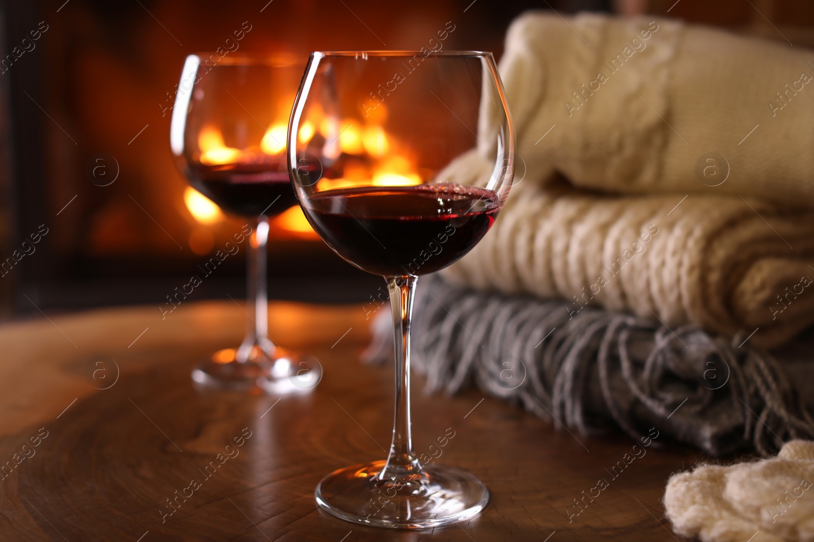 Photo of Glasses of wine, knitwear and blurred fireplace on background