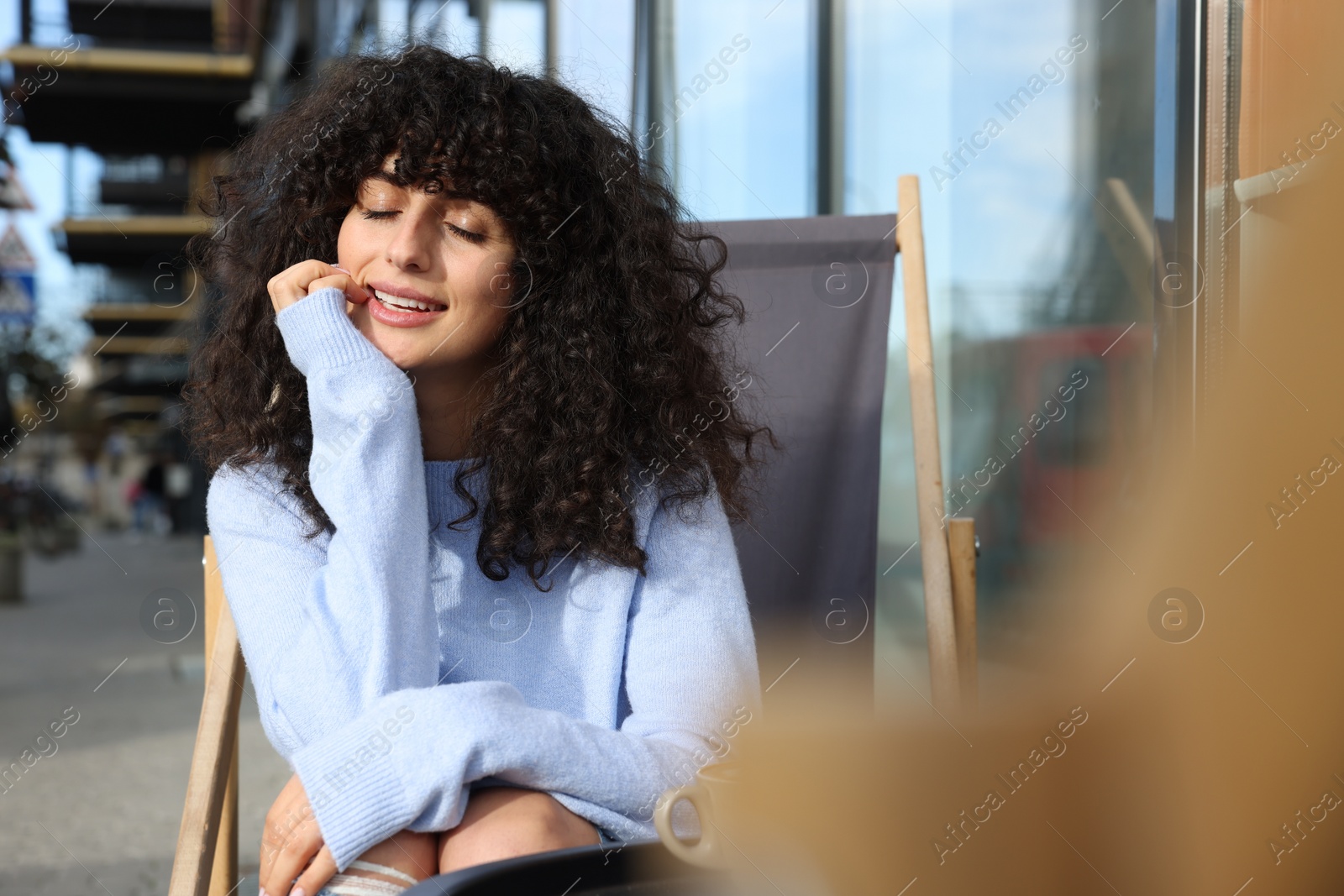 Photo of Happy young woman in stylish light blue sweater outdoors. Space for text