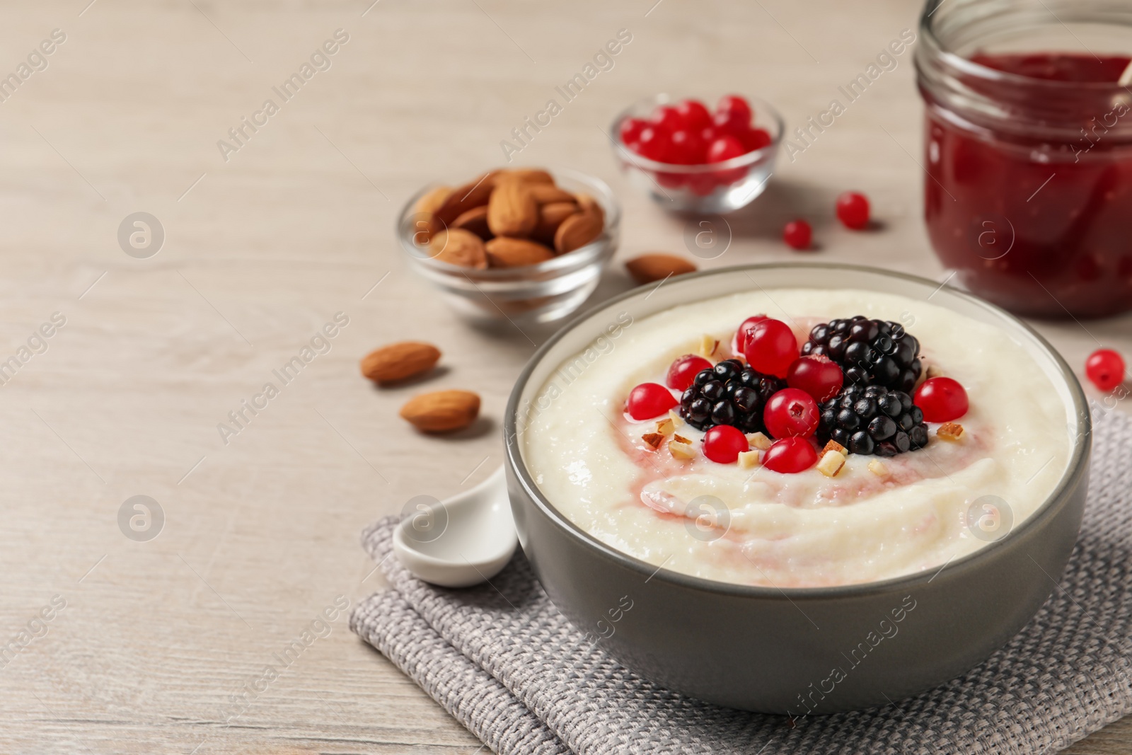 Photo of Delicious semolina pudding with berries on wooden table, space for text