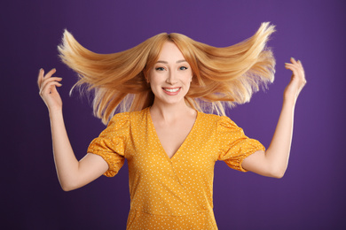 Photo of Beautiful young woman with blonde hair on purple background