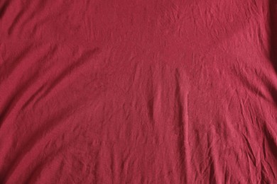 Crumpled dark red fabric as background, top view