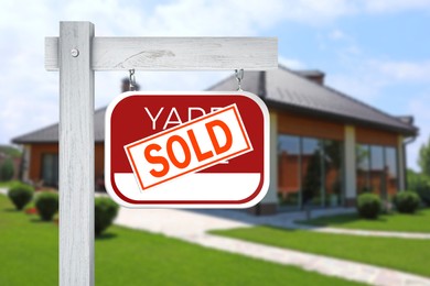 Image of Yard sale sign with Sold sticker near house