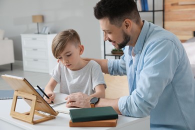 Boy with father doing homework at table indoors