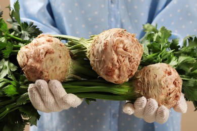 Photo of Woman holding raw celery roots, closeup view